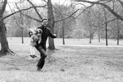 A father carries his daughter through a park.