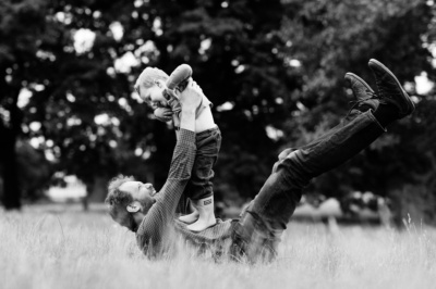 A father and child play in the grass.