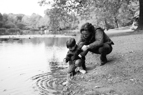 A father and his child play on the edge of a pond.