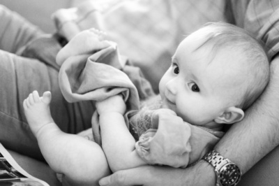 A father cradles his baby beside him.