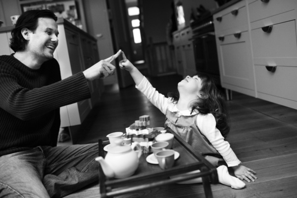 A father and daughter play games while holding a tea party.