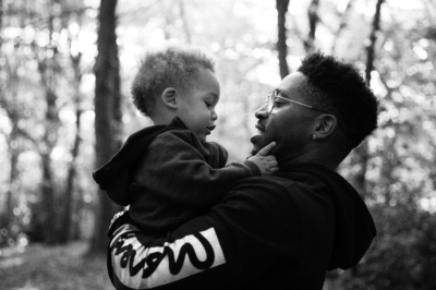 A father holds son in woodland.