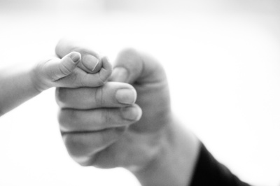 A newborn's finger curls around the finger of their parent.