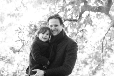 Father hugs his son with trees in the background.