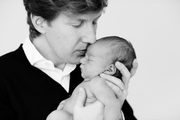 A father kisses the forehead of his newborn baby.