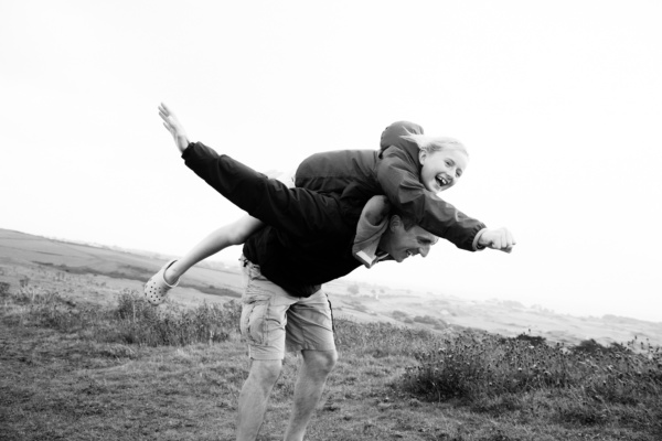 Father piggybacks daughter across field.