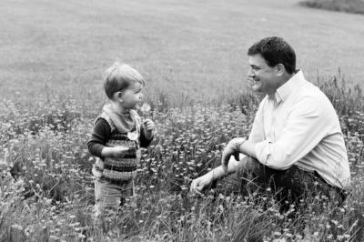 A father and his son play in a field of flowers.