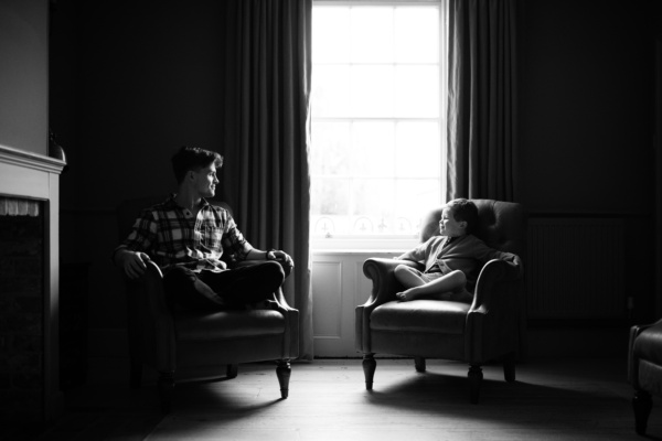 A father and won portrait at home in wing-backed chairs.