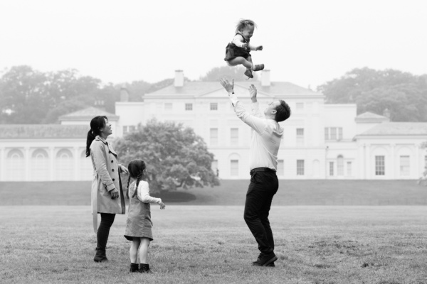 Father throws his baby into the air at family shoot at Kenwood House, London.