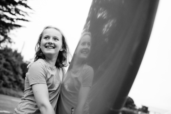 A girl carries surfboard.