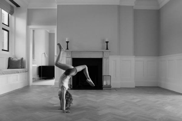 A girl does gymnastics in an empty room.