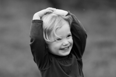 Girl giggles with her hands on her head.