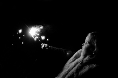 Girl holds a sparkler at night.