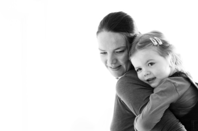 Girl hugs her mother in a black and white portrait.