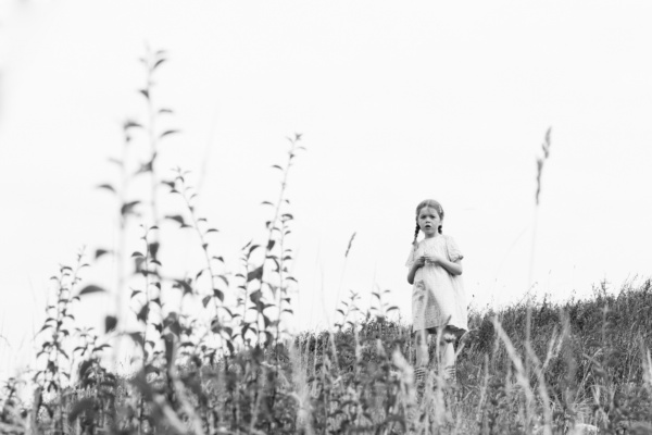 Girl stands in a field in a black and white family portrait.