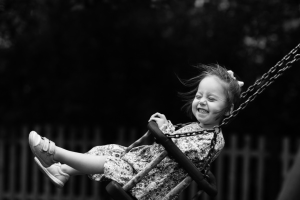 A girl kicks her legs on a swing.