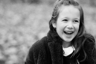 A black and white portrait of a girl laughing in a park.