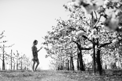 Girl looks at tree blossom.