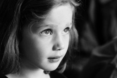 Girl looks up at light in a black and white portrait.