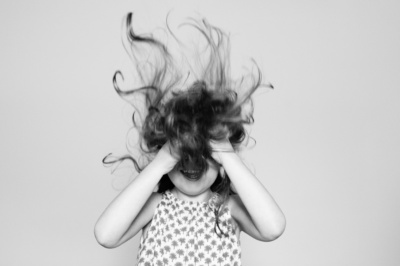 A girl messes up her hair in a black and white portrait.