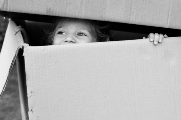 Girl peeps out of cardboard box.