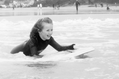 A girl rides a boogie board in Cornwall.