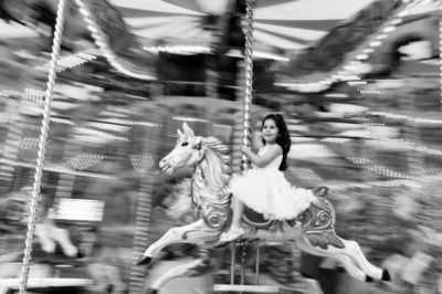 A girl rides a merry-go-round horse.