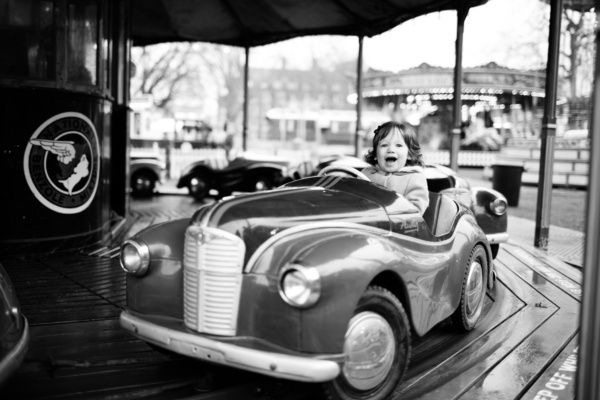 A smiling girl rides a merry-go-round car.