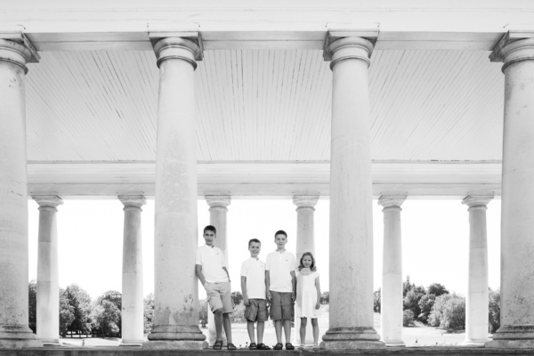 Four siblings stand together for a family portrait near columns in Greenwich.