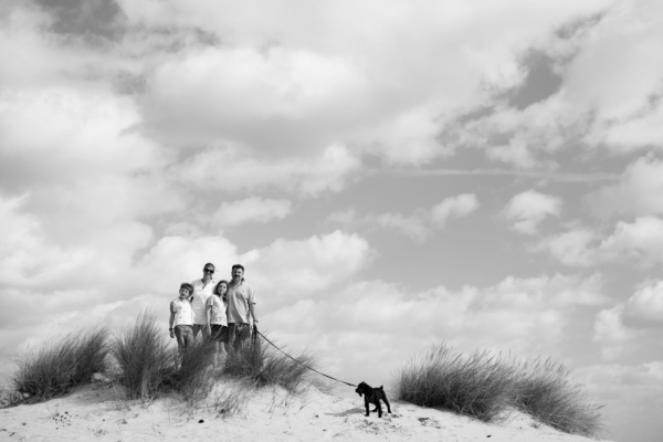 Portrait of a family of four and their dog on sand dunes.