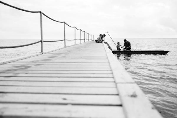 A london family swim off a jetty in the sea.