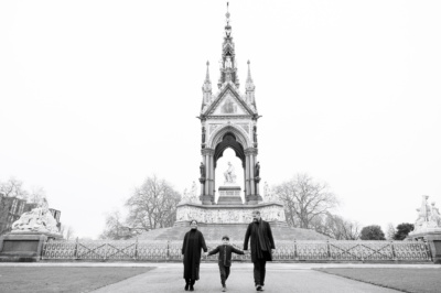 A family of three walk through a London park during their vacation shoot.