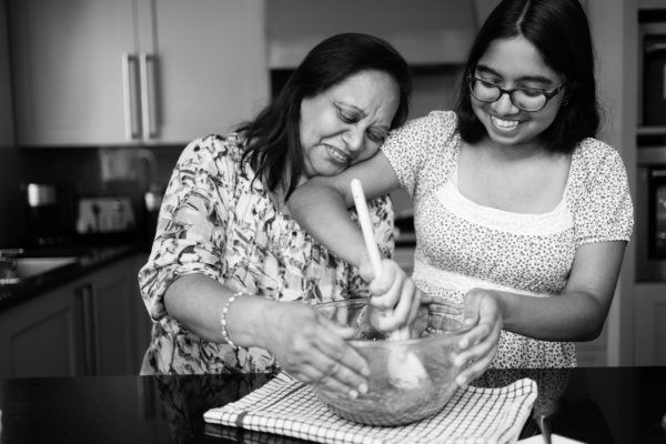 A mother and teenage daughter bake together.