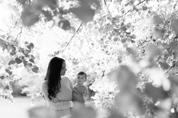 A portrait of a mother and her baby amongst leaves.