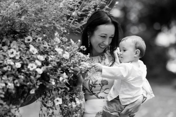 A mother and baby look at flowers together.