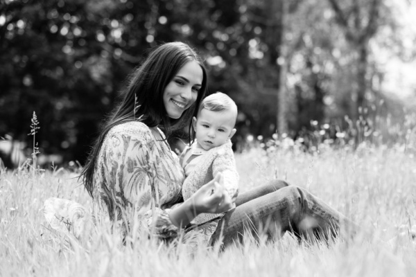 A mother and baby sit in a field of flowers.