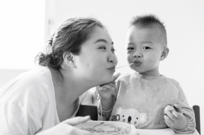 A mother and her child chew a string of spaghetti like lady and the tramp.