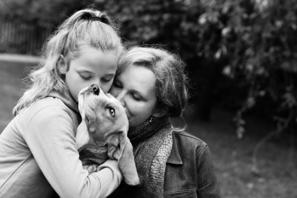 A mother and daughter cuddle the family dog.