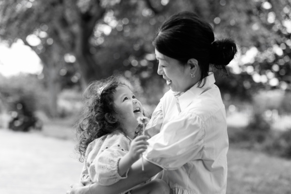 A mother cuddles her daughter, who is holding a flower.