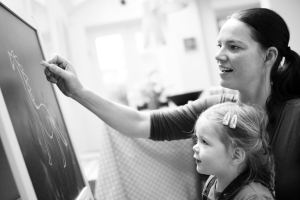 A mother and daughter draw on a blackboard.