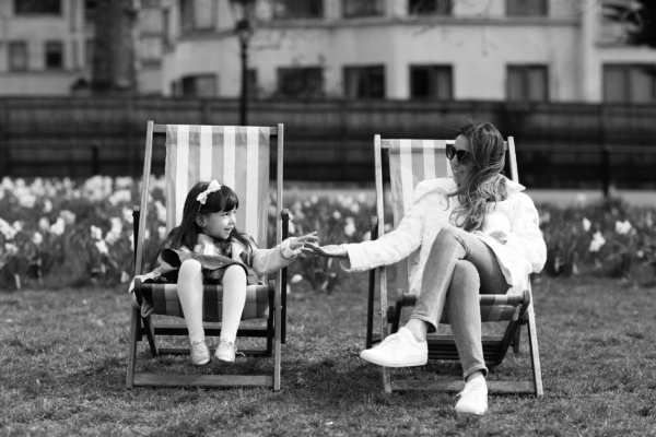 A mother and daughter sit in deckchairs in a London park during a vacation portrait shoot.