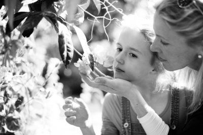 A mother and daughter look at tree blossom.