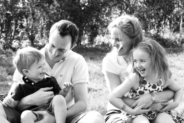 Mother, father and children play in a garden.