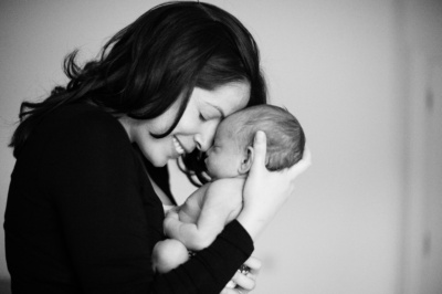 A joyful mother snuggles her newborn into her forehead.