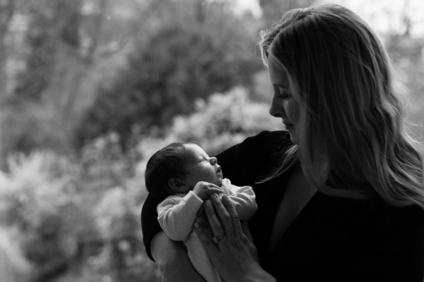 A mother holds her newborn baby outdoors.