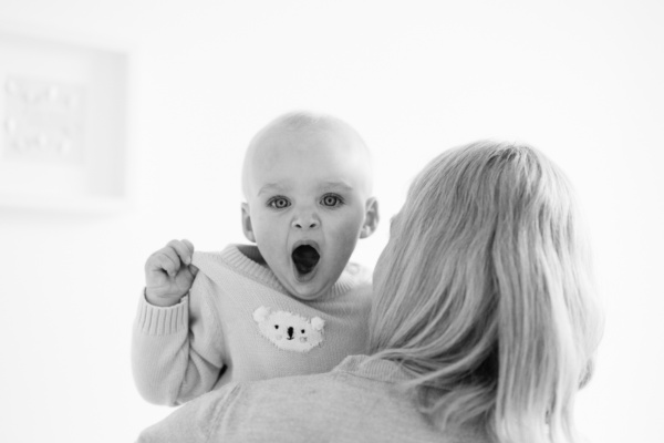 A mother holds her yawning baby.