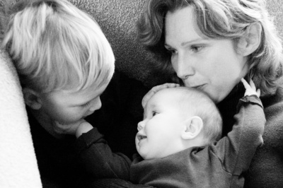 Mother kisses two children during a portrait shoot.