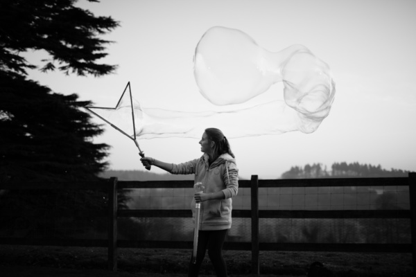 A mother makes a giant bubble in a garden.