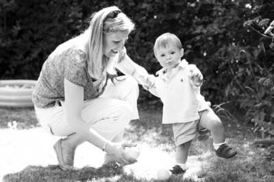 Mother plays ball with her son in the garden.