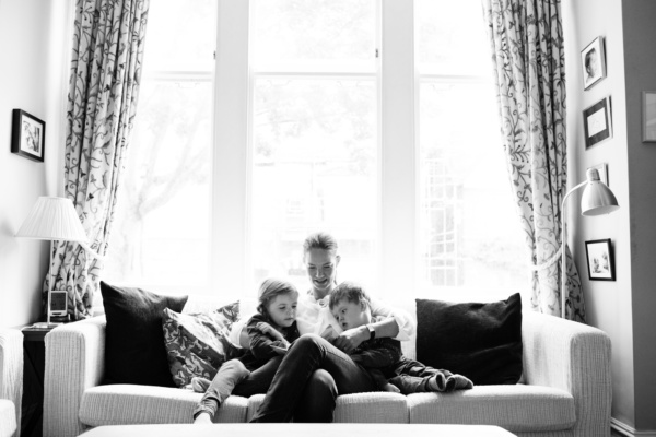 A mother reads with her two children on a sofa.